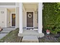 A well-kept townhome entrance featuring a covered porch, brown door with a wreath, and green landscaping at 8520 Quarton Dr, Raleigh, NC 27616