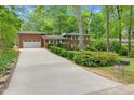Long driveway leading to a brick home with an attached garage surrounded by lush green landscaping at 905 Cindy St, Cary, NC 27511