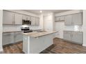 Well-lit kitchen featuring gray cabinets, granite countertops, stainless steel appliances and wood flooring at 112 Global Ave, Fuquay Varina, NC 27526