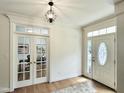 Bright foyer with hardwood floors, elegant lighting, and glass doors leading to an office at 113 Chesterfield Dr, Cary, NC 27513