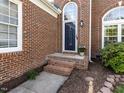 Inviting entryway with classic brick steps and decorative plants. Arched windows on either side at 117 Whitehaven Ln, Cary, NC 27519