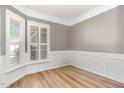 Elegant empty room with hardwood floors, white wainscoting, and plantation shutters at 1206 Areca Way, Durham, NC 27703