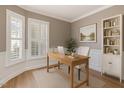 Brightly lit home office featuring hardwood floors, a built-in bookshelf, and a large window at 1206 Areca Way, Durham, NC 27703