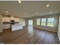 Open-concept living room and kitchen area with hardwood floors and ample natural light from the windows at 1214 Tredenham Way, Durham, NC 27703