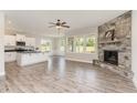 Open-concept living room with a stone fireplace, ceiling fan, and large windows providing ample natural light at 194 Spring Hill Church Rd, Lillington, NC 27546