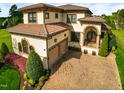 Lovely stucco house with a tile roof and a brick driveway surrounded by greenery at 20 Al Aqua Dr, Durham, NC 27707