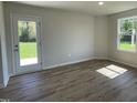 Living room showcasing natural light, wood-look flooring, neutral paint and access to the backyard through a glass door at 299 Phil Jack Rd, Dunn, NC 28334