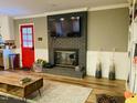 Cozy living room with a brick fireplace, hardwood floors, and modern furnishings, with a red door at 3018 Green Hill Dr, Chapel Hill, NC 27514