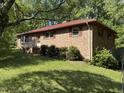 Quaint brick home featuring a red metal roof, traditional shutters, and mature landscaping at 311 N Nash St, Hillsborough, NC 27278
