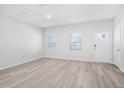 Bright living room featuring new hardwood floors, two windows, and a freshly painted white door at 3707 Rosebush Dr, Zebulon, NC 27597