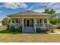 Inviting front porch with gray stairs and trim, complemented by an American flag, plants, and curb appeal at 7308 York, Mebane, NC 27302
