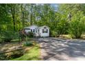 Cozy white cottage-style home surrounded by trees, featuring a well-manicured lawn at 107 Piquot Dr, Louisburg, NC 27549