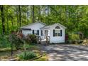 Charming cottage-style home with mature trees, a well-manicured lawn, and vibrant flowers at 107 Piquot Dr, Louisburg, NC 27549