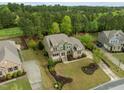 Aerial view of a brick and green home with mature landscaping, a long driveway, and a lush wooded backdrop at 1104 Covered Bridge Trl, Chapel Hill, NC 27517