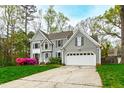 Charming two-story home featuring gray siding, attached garage, and mature trees at 1412 Amberton Ct, Raleigh, NC 27615
