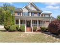 Charming two-story brick home featuring a welcoming front porch and lush landscaping at 192 Crestdale Dr, Clayton, NC 27520