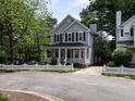 Charming two-story home featuring a white picket fence, covered porch, and landscaped yard with mature trees at 207 Reedhaven Dr, Cary, NC 27513