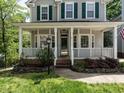 Inviting front porch with white columns and railing, stone-accented landscaping, and a well-maintained lawn at 207 Reedhaven Dr, Cary, NC 27513