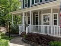Inviting front porch with white columns and railing, stone-accented landscaping, and a well-maintained lawn at 207 Reedhaven Dr, Cary, NC 27513
