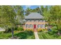 A beautifully landscaped brick house is framed by lush trees on a sunny day at 2545 Churchill Dr, Burlington, NC 27215