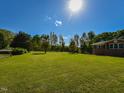 Large, sunny lawn on a property with mature trees and partial view of a brick home at 4170 Buckhorn Rd, Sanford, NC 27330