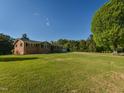Brick home on a sunny day surrounded by a well maintained lawn and plenty of shade trees at 4170 Buckhorn Rd, Sanford, NC 27330