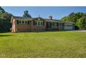 Charming brick home featuring black shutters and an attached garage situated on a spacious lawn at 4170 Buckhorn Rd, Sanford, NC 27330