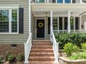 A lovely front entrance with brick steps, a wreath, and a covered porch at 504 Cameron Glen Dr, Apex, NC 27502
