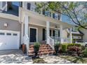 Front porch featuring brick steps, white columns and railings, and a black front door at 5605 Cary Glen Blvd, Cary, NC 27519