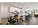 Open-concept kitchen with white cabinets, stainless steel appliances, large island, and wood floors at 714 Andrade Dr, Fuquay Varina, NC 27526