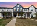 Inviting townhome exterior features a landscaped yard and charming front porch at sunset at 717 Silo Park Dr, Wake Forest, NC 27587