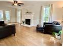 Bright living room with hardwood floors, white fireplace, ceiling fan, and French doors at 1002 Springmill Ct, Apex, NC 27502