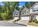 Street view of well-maintained townhomes with two-car garages, stone accents, and mature trees at 1230 Wingstem Pl, Raleigh, NC 27607