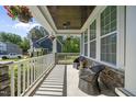 Inviting covered porch featuring stone accents, comfortable seating, and hanging flower baskets at 140 Barletta Ct, Clayton, NC 27527