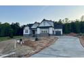 Charming home showcasing a concrete driveway, gray siding and stone accents against a wooded backdrop at 1403 Cottondale Lane, Wake Forest, NC 27587