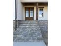 Inviting front entrance with stone steps leading to a wood-framed glass front door and craftsman style details at 1403 Cottondale Lane, Wake Forest, NC 27587
