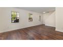 Bright open living room with hardwood floors, neutral walls, two large windows, and outside access at 2024 Spring Creek Dr, Durham, NC 27704