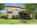 Back exterior featuring a cozy screened-in porch, well-maintained lawn, and mature landscaping at 2053 Monthaven Dr, Wake Forest, NC 27587