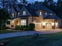 Rear exterior view of a beige two-story home with a three-car garage illuminated at dusk at 2317 Emerald Woods Dr, Wake Forest, NC 27587