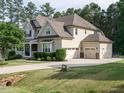 Rear exterior view of a beige two-story home with a three-car garage and well-kept lawn at 2317 Emerald Woods Dr, Wake Forest, NC 27587