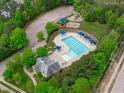 Aerial view of community pool, playground, parking and pool house surrounded by lush trees at 2832 Cameron Pond Dr, Cary, NC 27519