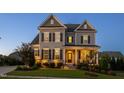 Two-story home at dusk with stone accents, covered front porch and manicured lawn at 3209 Star Gazing Ct, Wake Forest, NC 27587