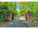 Gated entrance showing the long driveway through mature trees providing privacy at 3214 Saddle Club Rd, Mebane, NC 27302