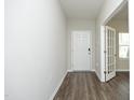 A modern hallway with gray walls, wood-look flooring, and a doorway leading to another room with bright windows at 3804 Delves Ln, Raleigh, NC 27616