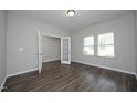 A bright, open room featuring wood flooring, gray walls, and a doorway with glass french doors, and many windows at 3804 Delves Ln, Raleigh, NC 27616