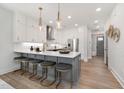 Bright kitchen featuring white cabinetry, stainless steel appliances, island with bar seating and stylish pendant lighting at 3922 Lost Fawn Ct, Raleigh, NC 27612