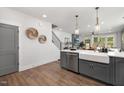 Open concept kitchen featuring white quartz countertops, grey cabinets, stainless steel dishwasher and farmhouse sink at 3922 Lost Fawn Ct, Raleigh, NC 27612