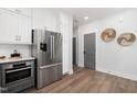 Elegant kitchen with stainless steel refrigerator, built-in oven, white cabinets and hardwood flooring at 3922 Lost Fawn Ct, Raleigh, NC 27612