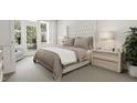Cozy bedroom with a plush, tufted headboard, neutral tones, and French doors leading to an outdoor area at 3926 Lost Fawn Ct, Raleigh, NC 27612