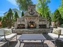 Outdoor stone fireplace with chairs and a table for entertaining guests at 4210 Falls River Ave, Raleigh, NC 27614